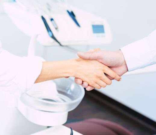 two hands which expressing some kind of bargain made in the dentist room in front of the dentist chair.