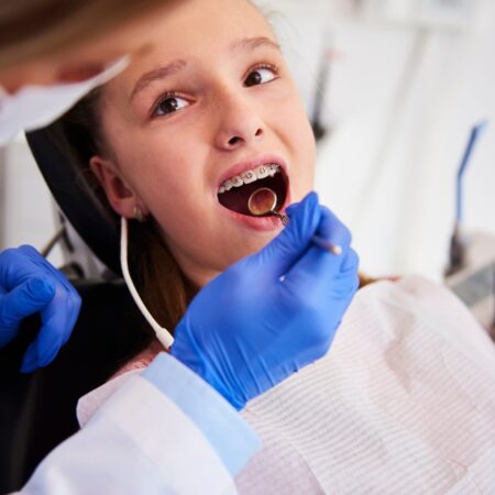 Part of orthodontist examining child's teeth in dentist's office