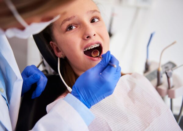 Part of orthodontist examining child's teeth in dentist's office