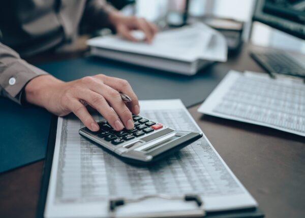 Investors working on desk office and using a calculator to calculate balance, profit, currency and cost. Accounting and  Financial concept.