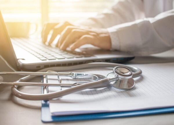 Stethoscope on prescription clipboard and Doctor working an Laptop on desk in hospital, Healthcare and medical concept, vintage color, selective focus