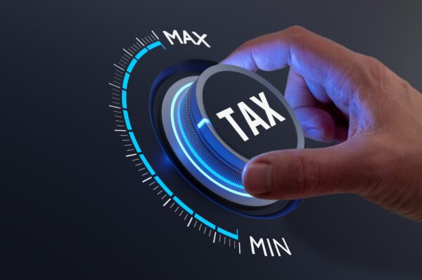 Tax reduction and deduction for businesses and individuals. Concept with hand turning knob to low taxation rate. Return form, exemptions, incentives.