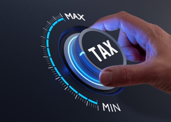 Tax reduction and deduction for businesses and individuals. Concept with hand turning knob to low taxation rate. Return form, exemptions, incentives.