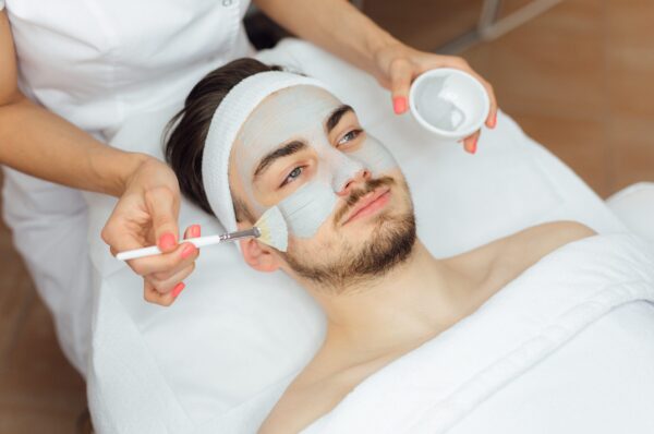 Unshaven man having cosmetic mask care in spa salon, side, top view - Image