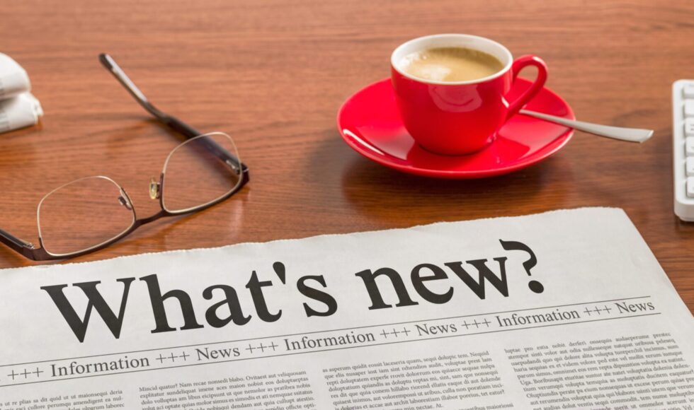 a newspaper with a cup of coffee and glasses on a table