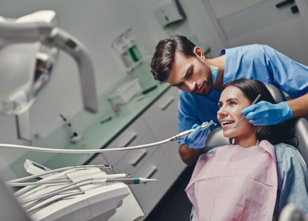 Attractive young woman in stomatology clinic with male dentist. Healthy teeth concept.