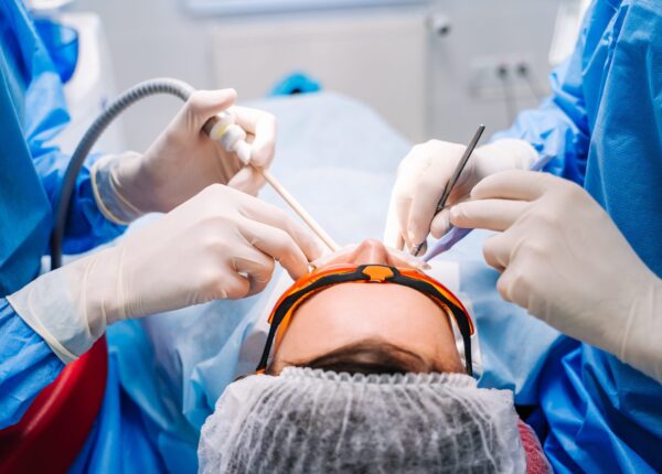 Dentist in uniform perform dental treatment on a patient at modern stomatology office. Selective focus. View from the back. Closeup.